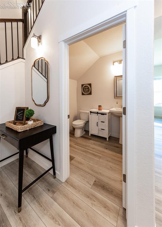 Image 9 of 49: Half bathroom with light wood-style floors and vaulted ceiling