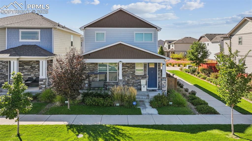 Caption: Craftsman-style house with stone siding, a front yard, a residential view, and a porch