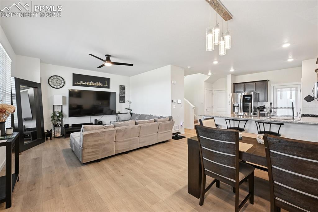 Image 15 of 35: Living room featuring light wood finished floors, a ceiling fan, and stairw