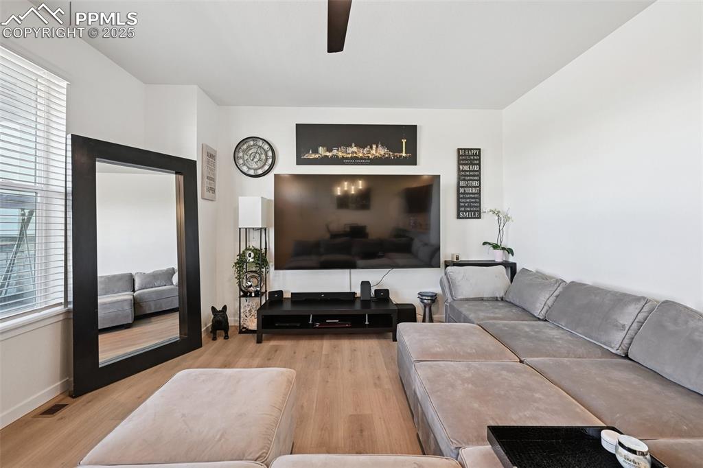 Image 16 of 35: Living area with light wood-style floors and a ceiling fan