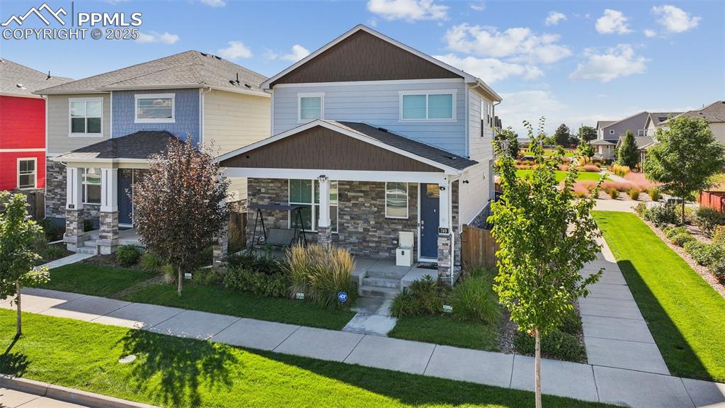 Image 2 of 35: Craftsman-style home with stone siding and a front lawn