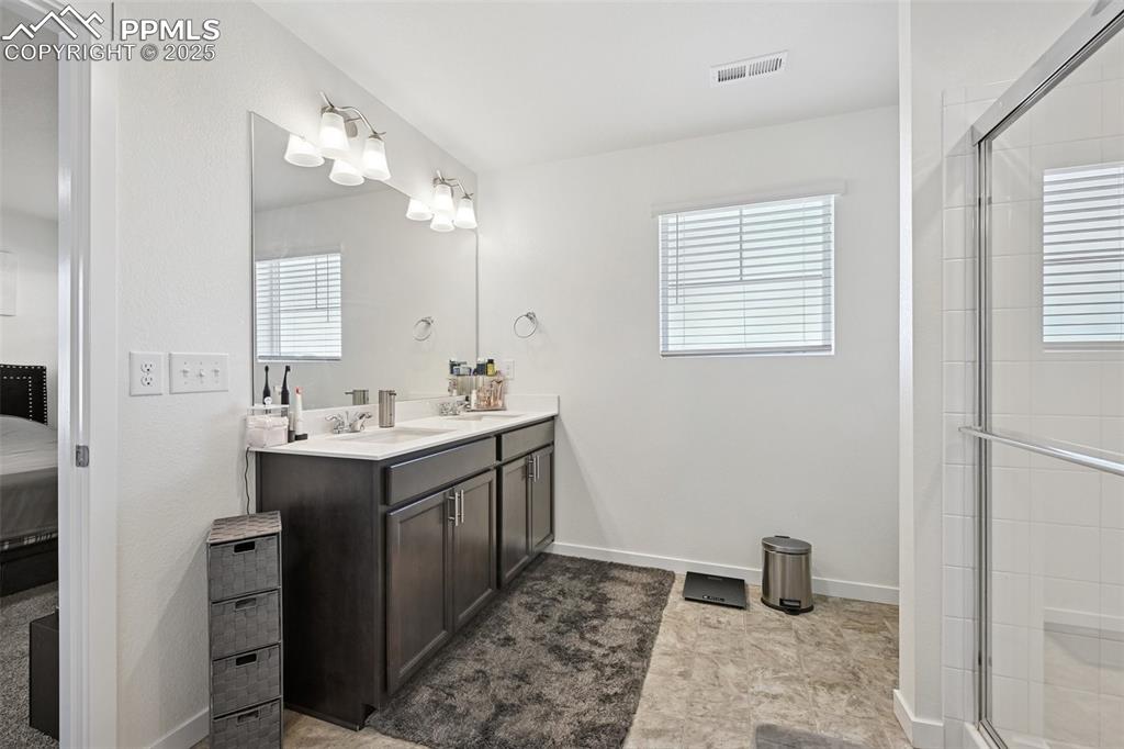 Image 28 of 35: Ensuite bathroom with double vanity, a shower stall, and healthy amount of