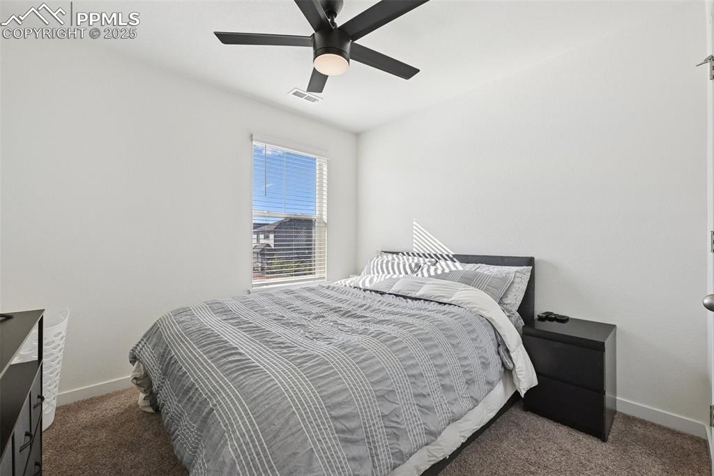 Image 32 of 35: Bedroom with dark colored carpet and a ceiling fan