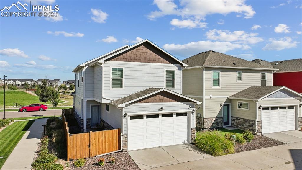 Image 6 of 35: View of front facade featuring a garage, driveway, stone siding, and a resi