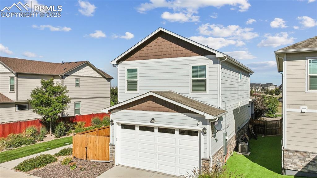 Image 7 of 35: View of front facade with concrete driveway, roof with shingles, and stone
