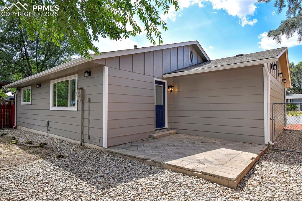 Image 20 of 25: Back of property with a patio area, a shingled roof, board and batten sidin