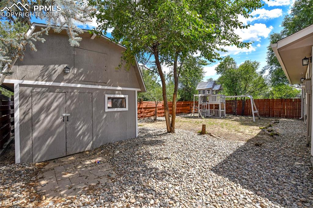 Image 21 of 25: Fenced backyard featuring a playground and a shed
