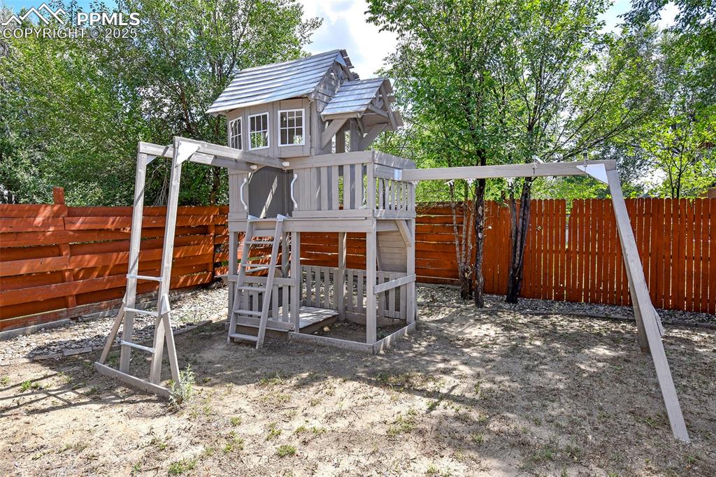 Image 22 of 25: Fenced backyard with a playground