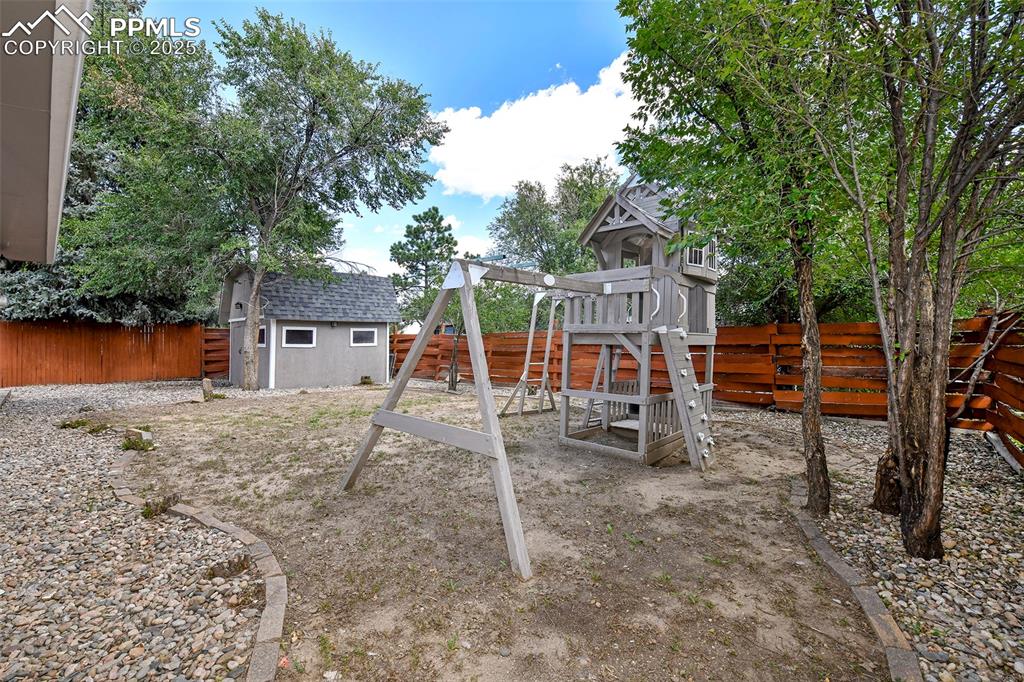 Image 23 of 25: View of jungle gym featuring a fenced backyard and a storage shed