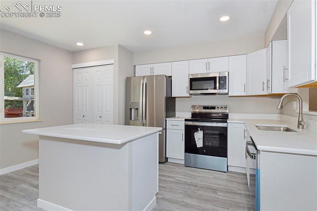 Image 3 of 25: Kitchen with stainless steel appliances, a center island, recessed lighting