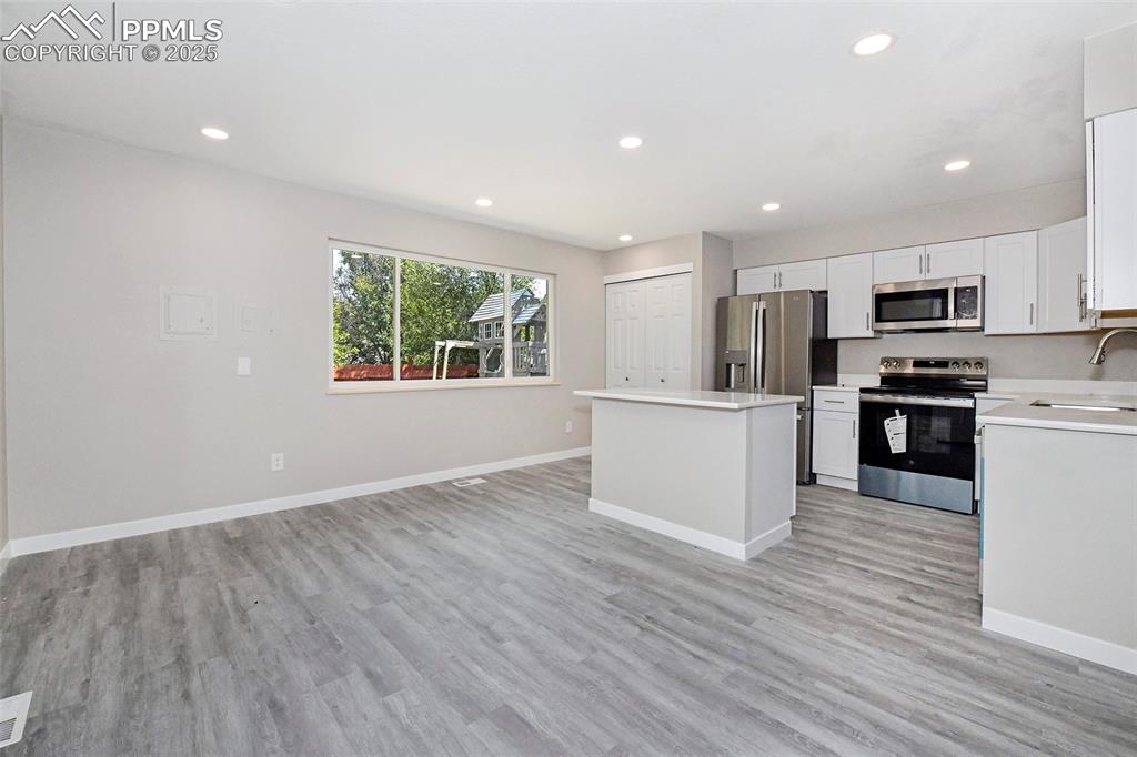 Image 4 of 25: Kitchen with stainless steel appliances, recessed lighting, white cabinetry