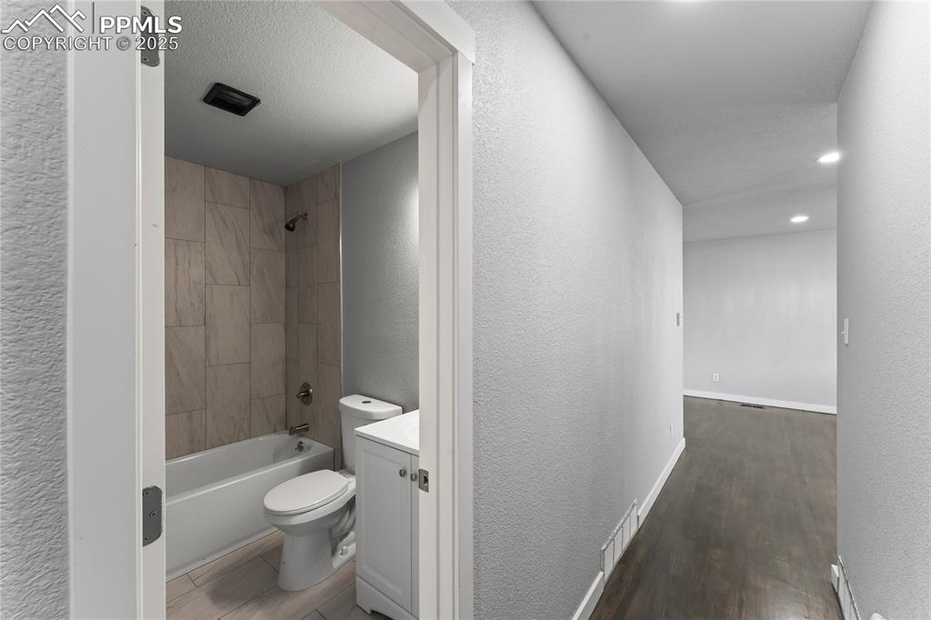Image 11 of 36: Bathroom featuring vanity, wood finished floors, shower / bath combination,