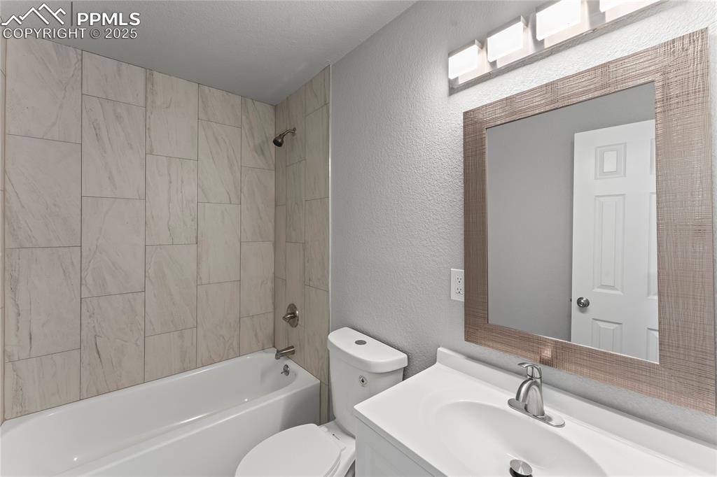 Image 12 of 36: Full bathroom with vanity, tub / shower combination, and a textured wall