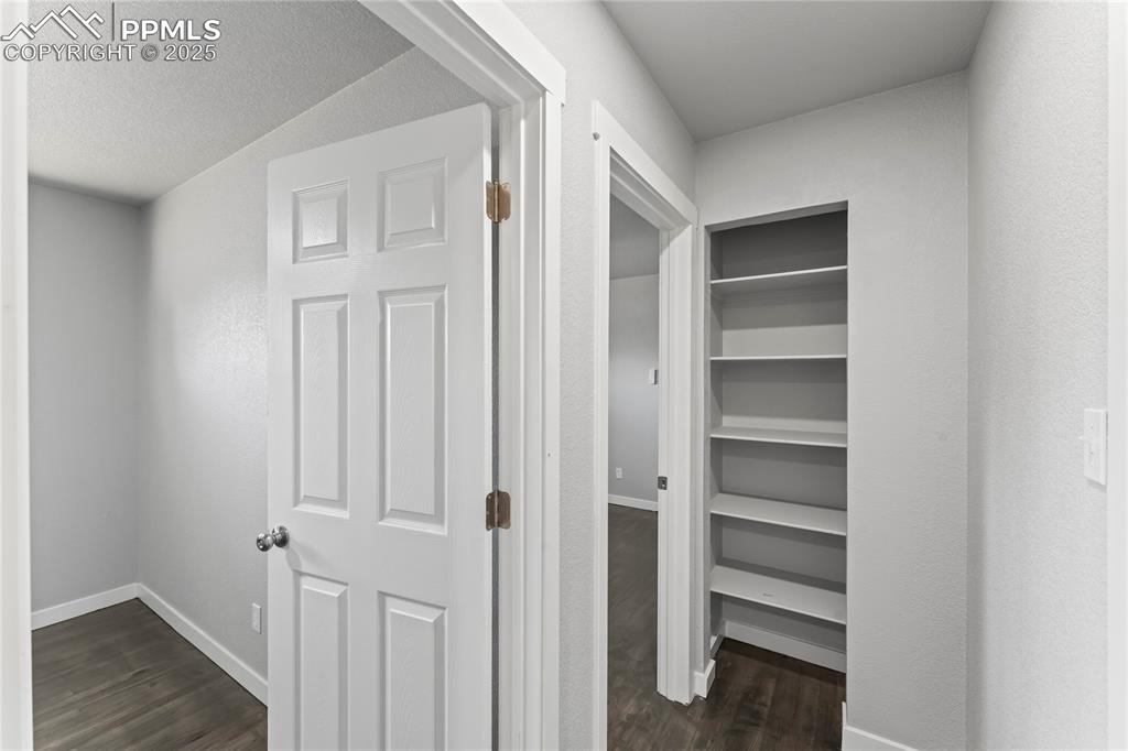 Image 13 of 36: Hallway featuring dark wood-style floors and baseboards