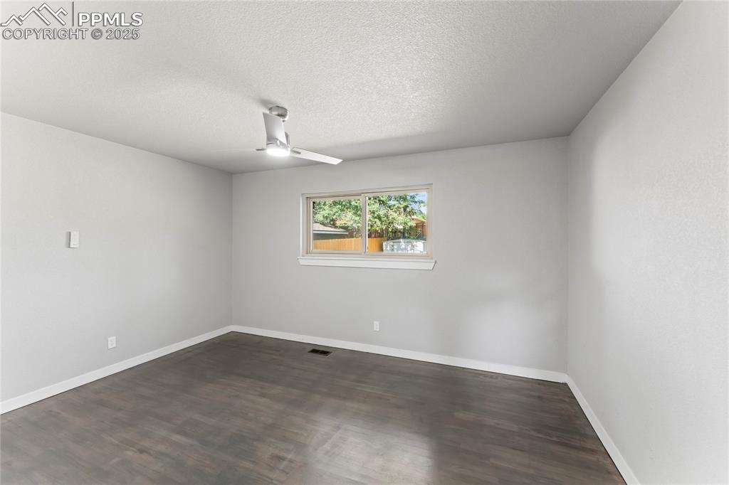 Image 17 of 36: Spare room with ceiling fan, dark wood-style floors, and a textured ceiling