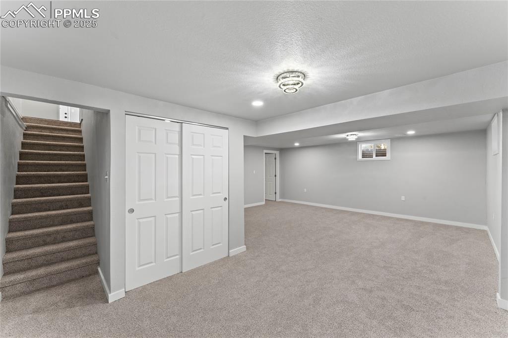 Image 21 of 36: Finished below grade area with carpet floors, stairway, a textured ceiling,