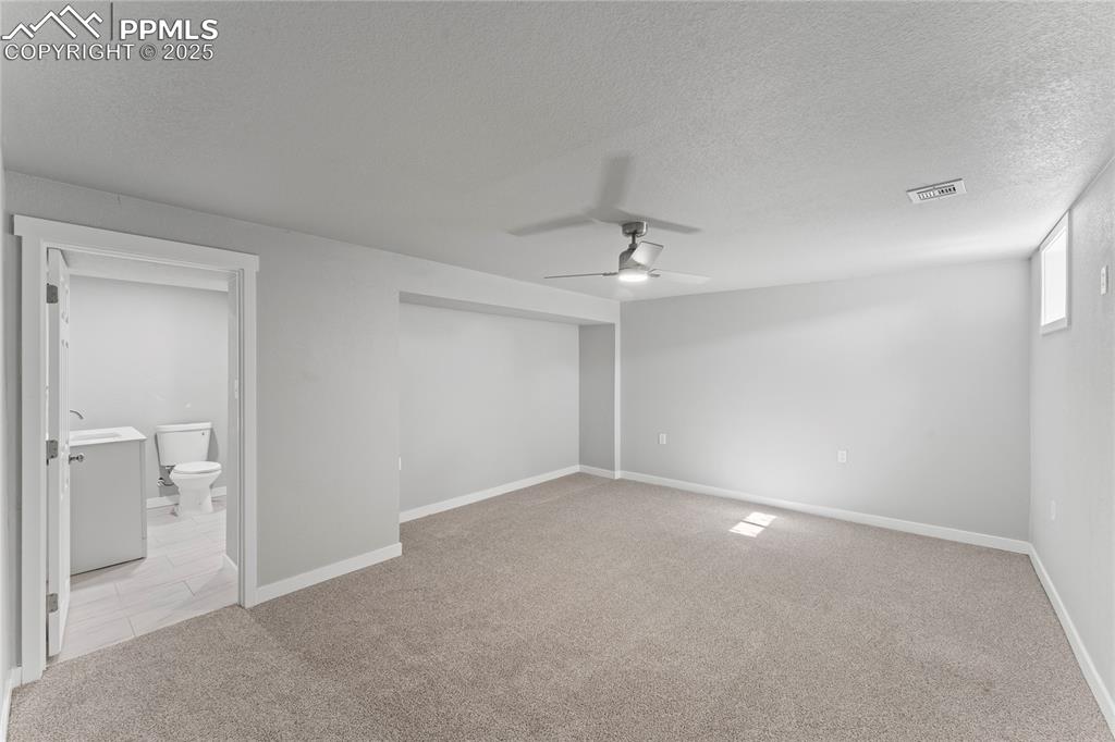 Image 25 of 36: Unfurnished bedroom featuring light carpet, a textured ceiling, ensuite bat