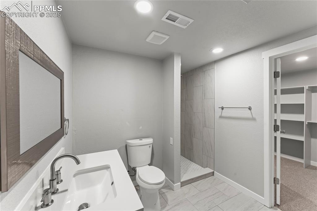 Image 27 of 36: Full bathroom with a tile shower, recessed lighting, a closet, and marble f