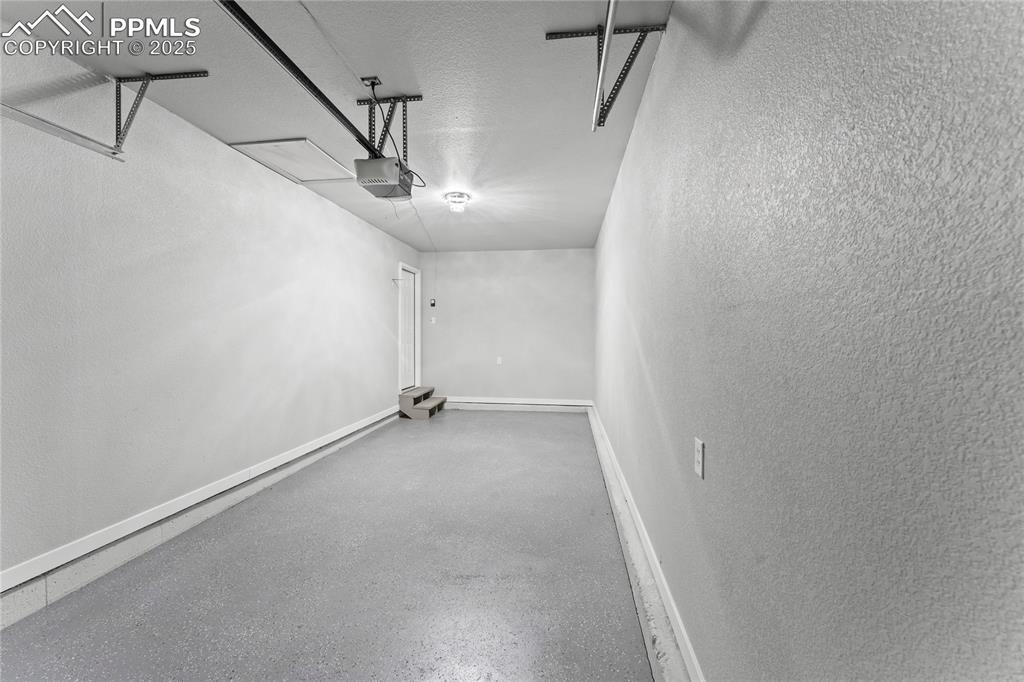 Image 30 of 36: Garage featuring a garage door opener and a textured wall
