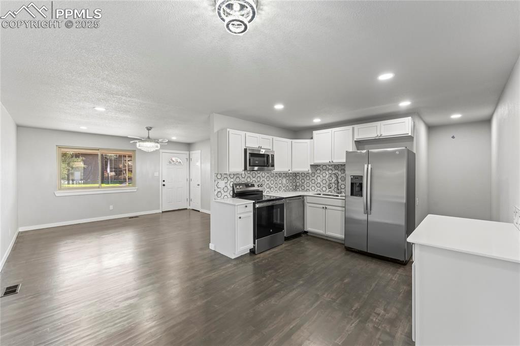 Image 6 of 36: Kitchen featuring appliances with stainless steel finishes, decorative back