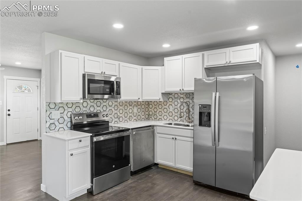 Image 8 of 36: Kitchen with stainless steel appliances, white cabinets, light countertops,