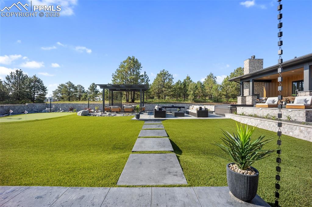 Image 48 of 50: Backyard features low maintenance turf, putting green, hot tub and pergola.