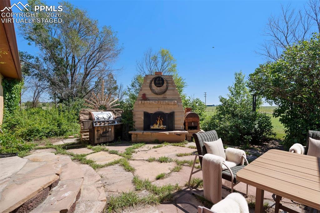Image 39 of 50: virtually staged Stone patio featuring an outdoor fireplace with a prominen