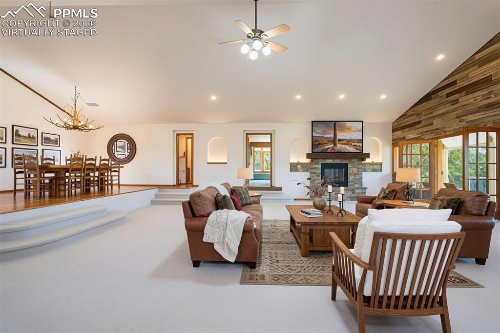 Image 8 of 50: virtually staged Vaulted ceiling living area featuring a stone fireplace wi