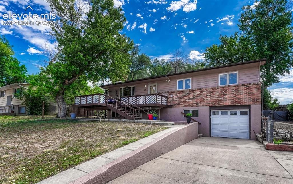 Caption: Ranch style residence featuring a brick and stucco siding exterior, an attached garage, and a raised