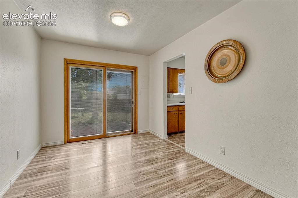 Image 11 of 50: Laminate flooring, featuring a sliding glass door with wood trim, offering 