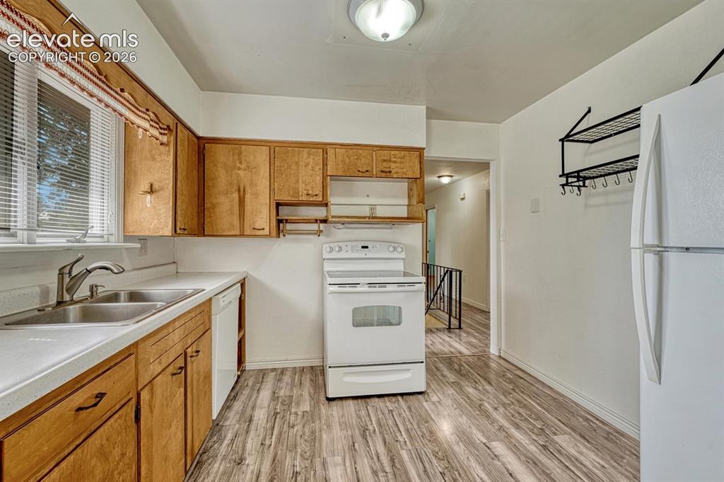 Image 12 of 50: Kitchen featuring wood cabinetry, white countertops, a stainless steel doub