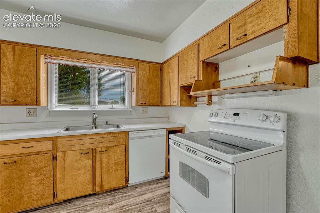 Image 13 of 50: Kitchen featuring wood-finish cabinetry, light-toned countertops, a stainle