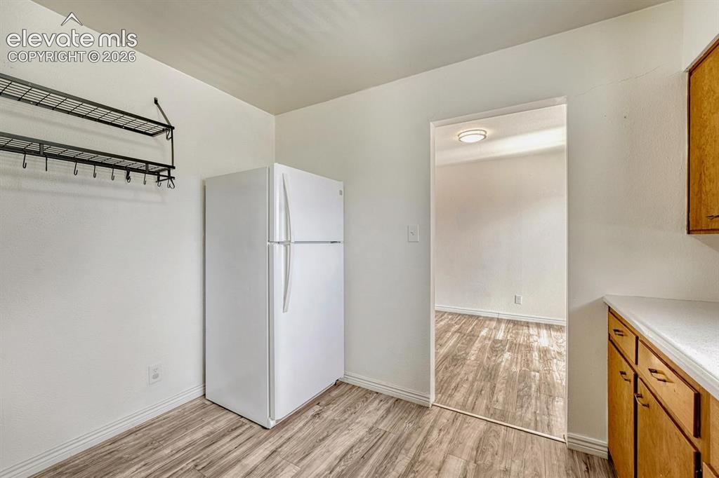 Image 16 of 50: Kitchen area featuring laninate flooring, light-toned cabinetry, and a whit