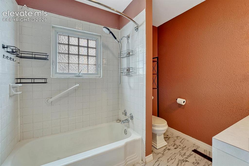 Image 18 of 50: Bathroom with white tile shower surround and a glass block window