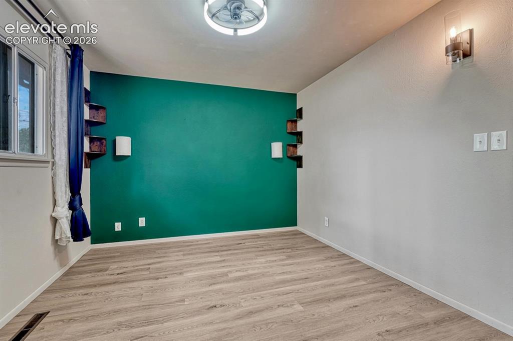 Image 21 of 50: Room featuring laminate flooring and a distinctive accent wall