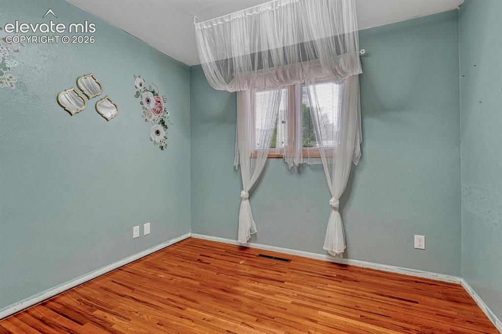 Image 25 of 50: Room featuring wood-finish flooring, light blue walls, and a window with wo