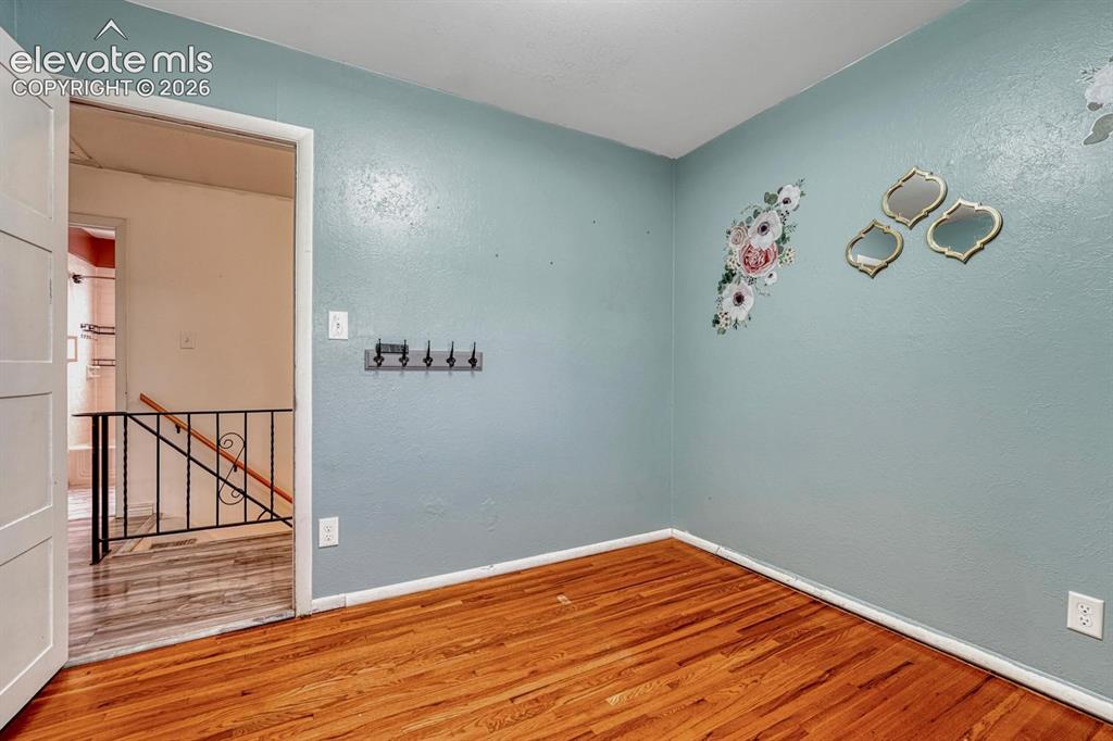 Image 26 of 50: Room featuring wood flooring, light blue wall color, white baseboards, and 