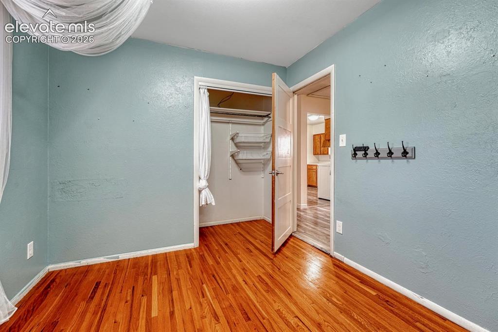 Image 27 of 50: Hardwood flooring throughout, a closet with built-in shelving, and a wall-m