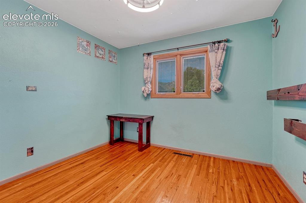 Image 28 of 50: Bright room featuring wood-finish flooring, a double window with wood trim,