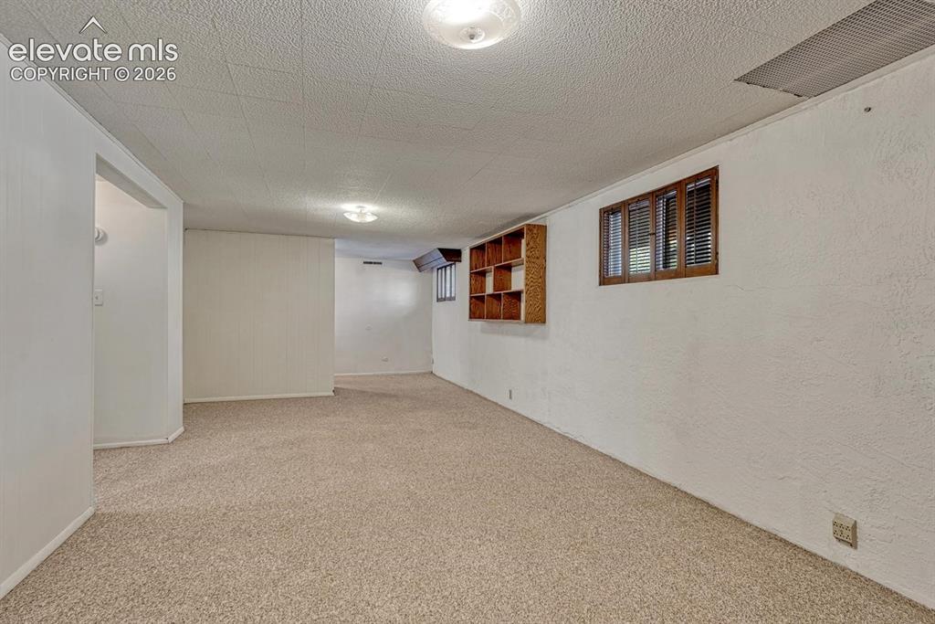 Image 34 of 50: Spacious room featuring carpeting, white textured walls,