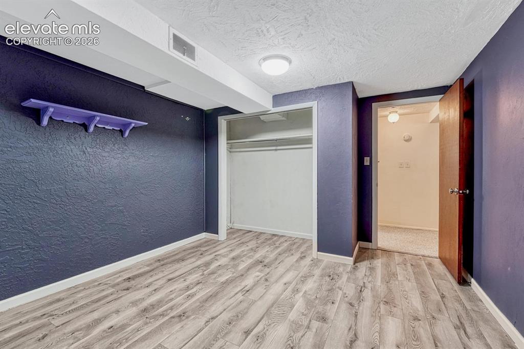 Image 37 of 50: Room featuring wood-finish flooring, a built-in closet with shelving and ha