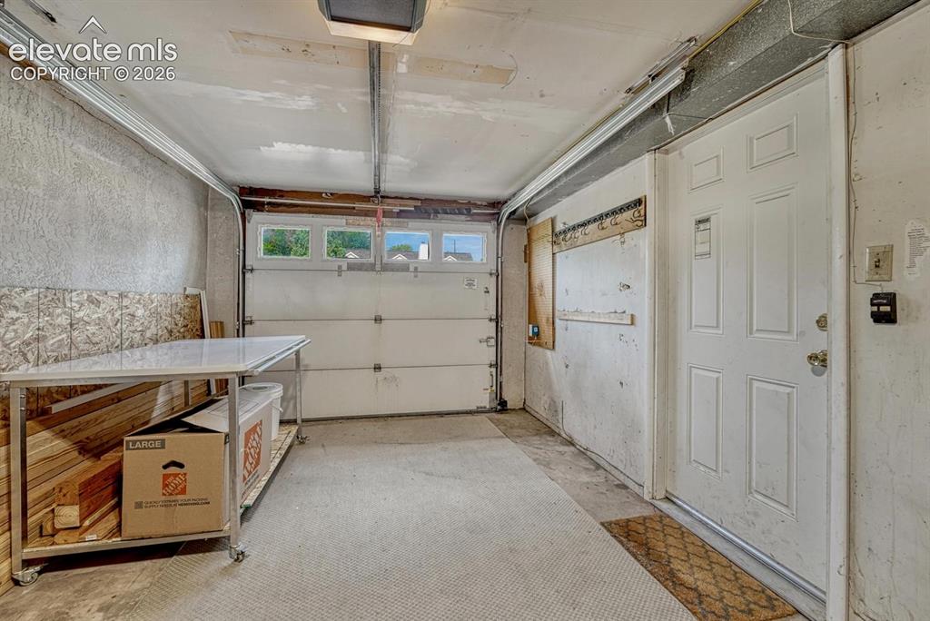 Image 40 of 50: Garage interior with overhead lighting, a paneled entry door, and an overhe