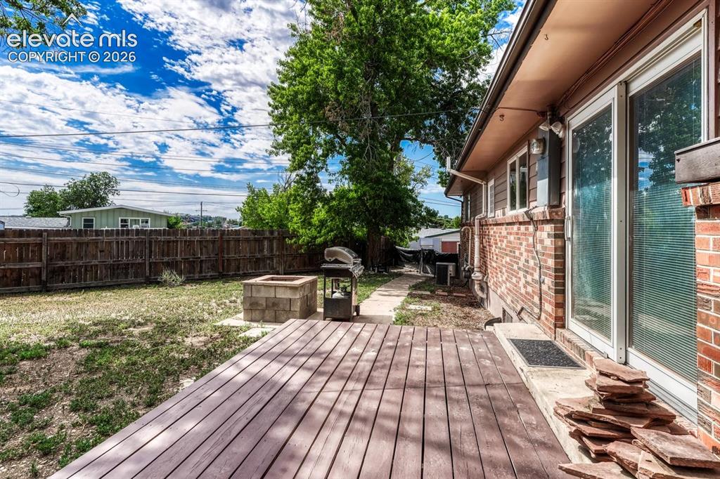 Image 41 of 50: Backyard outdoor deck with wood-finish decking, brick exterior, sliding gla