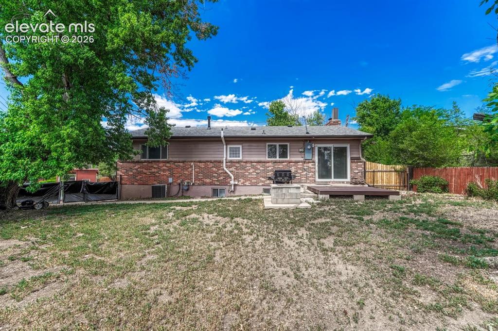 Image 42 of 50: Expansive backyard with a wood deck, sliding glass door access, partial bri
