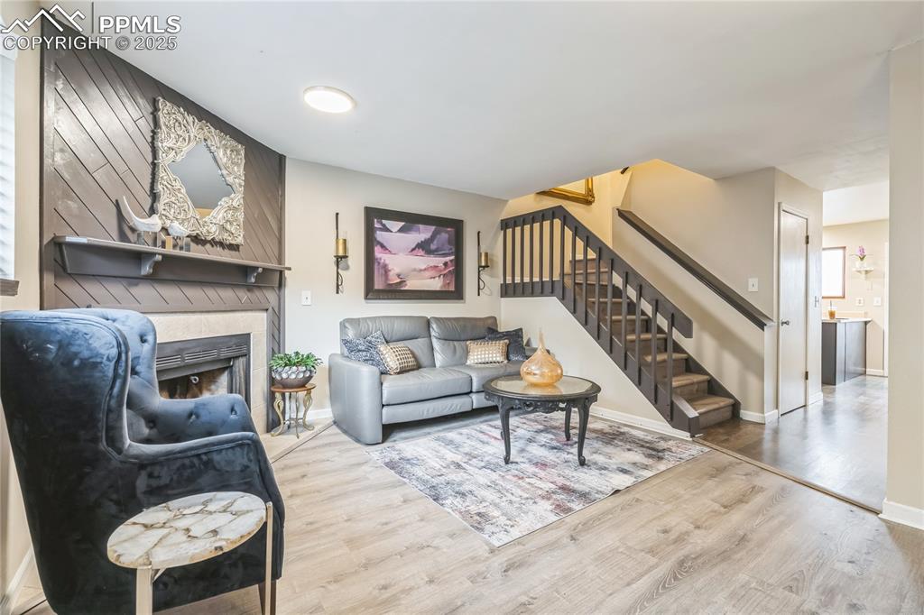 Image 3 of 21: Living room featuring wood finished floors, a lit fireplace, and stairs