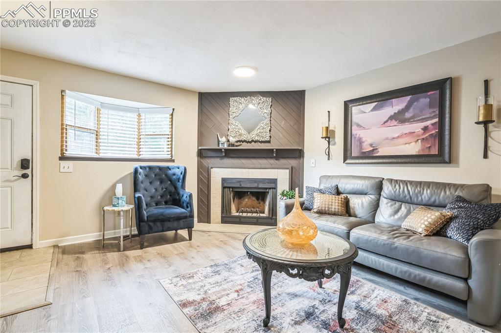 Image 4 of 21: Living room with wood finished floors and a tile fireplace