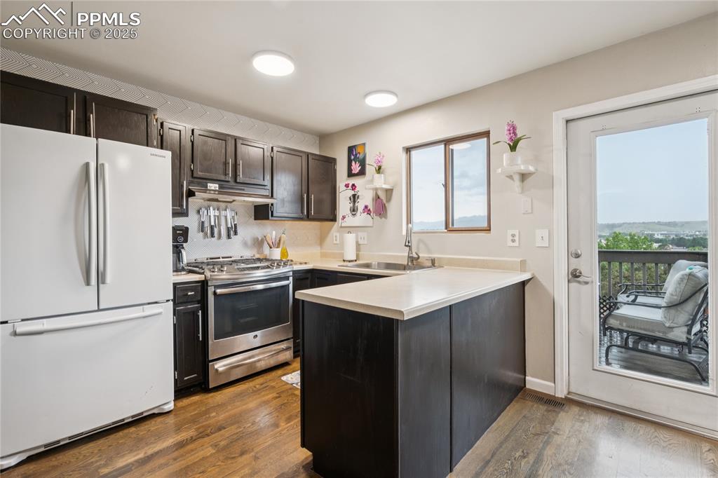 Image 6 of 21: Kitchen featuring freestanding refrigerator, a peninsula, stainless steel r