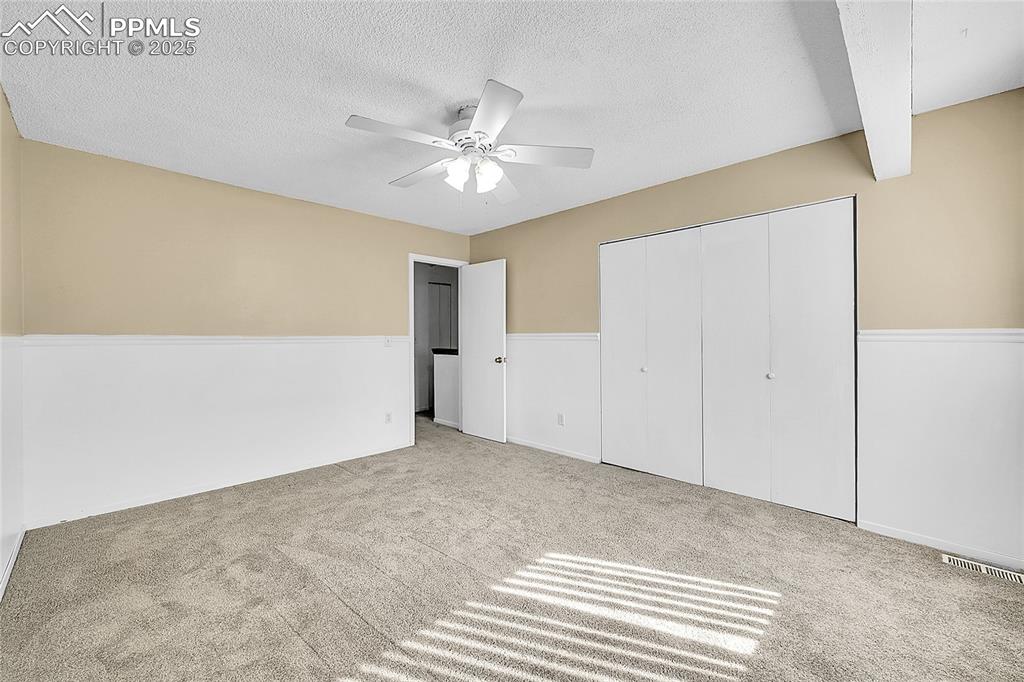 Image 10 of 12: Unfurnished bedroom with carpet flooring, a textured ceiling, a closet, and