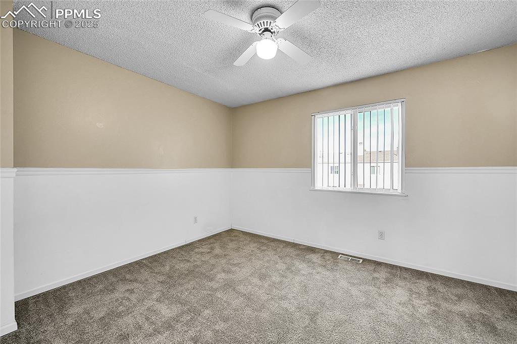 Image 11 of 12: Spare room with carpet, a textured ceiling, and a ceiling fan