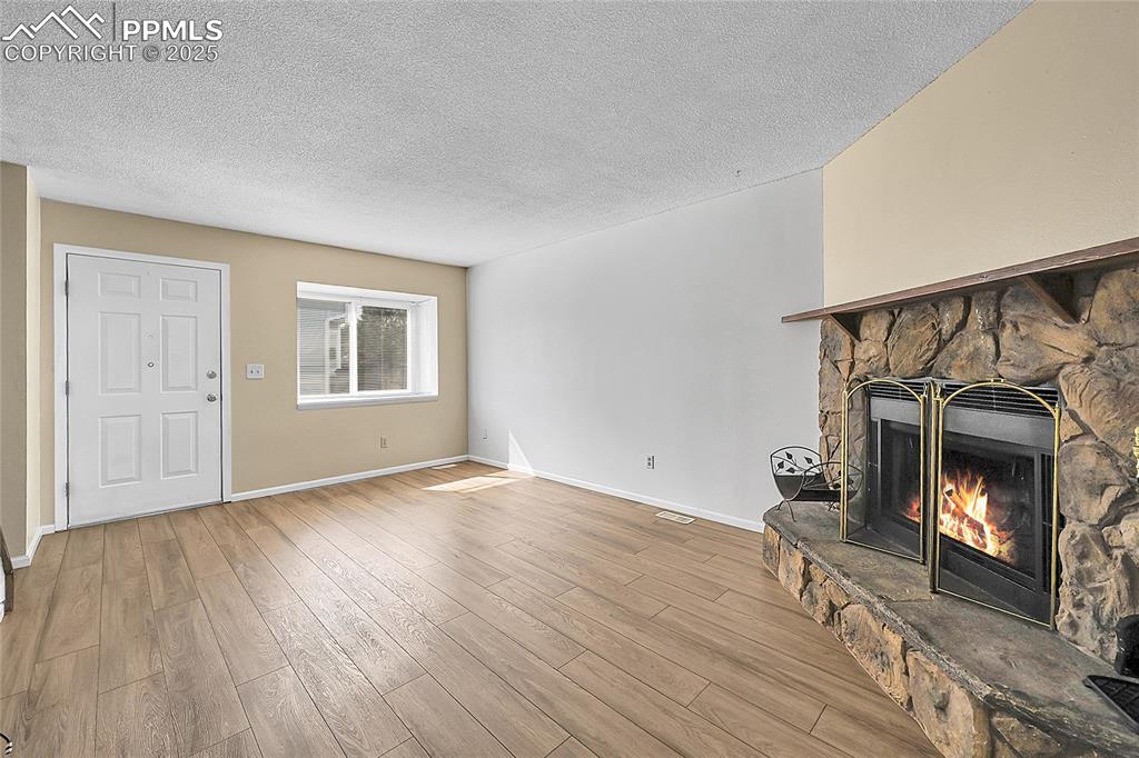 Image 5 of 12: Unfurnished living room featuring a fireplace, light wood-style floors, and